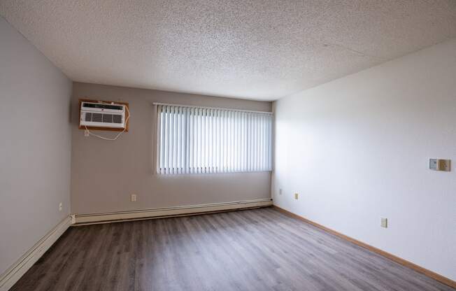 the living room of an empty apartment with wood flooring and a window