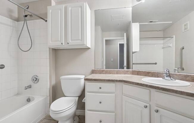 Edinburgh bathroom with a toilet, counter, sink, and mirror at Encore at Buckingham Apartments in Richardson, TX