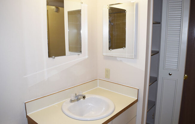 a bathroom with a sink and two mirrors at Seville Apartments in Kalamazoo, MI 49009