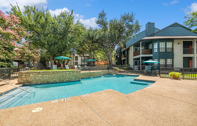 Community Swimming Pool with Pool Furniture at Bridges at Deer Run Apartments in Dallas, TX.