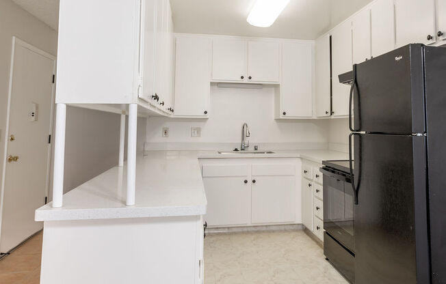 an empty kitchen with black appliances and white cabinets