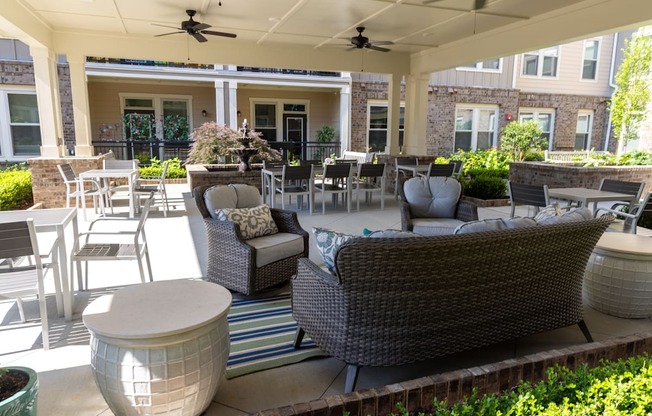 a patio with couches chairs and tables in front of a building