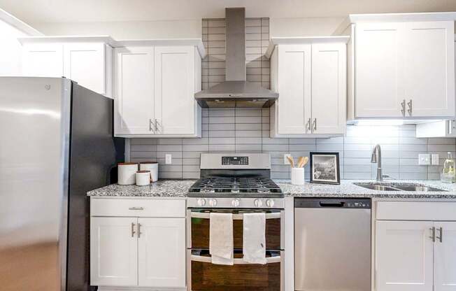 A modern kitchen with white cabinets and a black refrigerator.