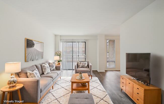 A living room with a grey couch, a wooden coffee table, and a television.