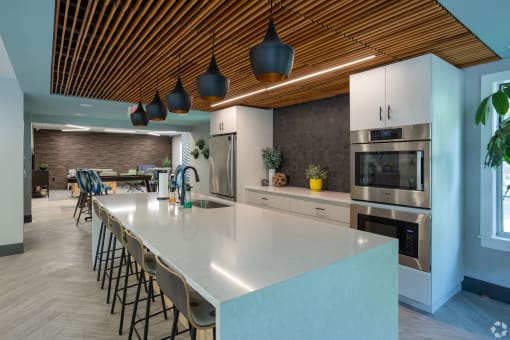 a large kitchen with a large white counter top and a dining room with a table