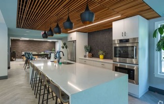 a large kitchen with a large white counter top and a dining room with a table