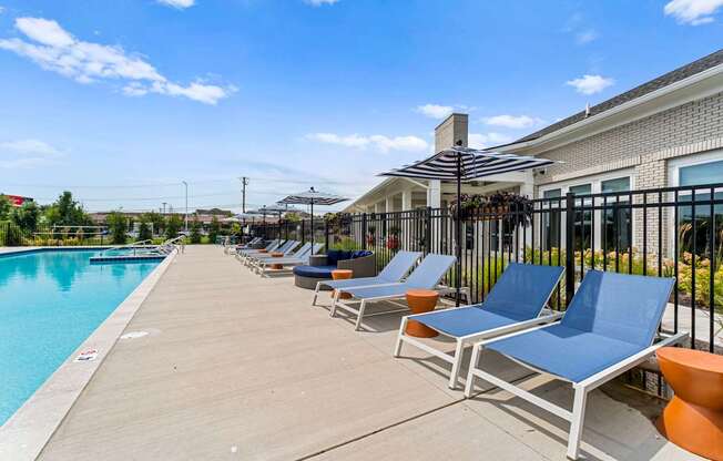 A poolside area with sun loungers and a building in the background.