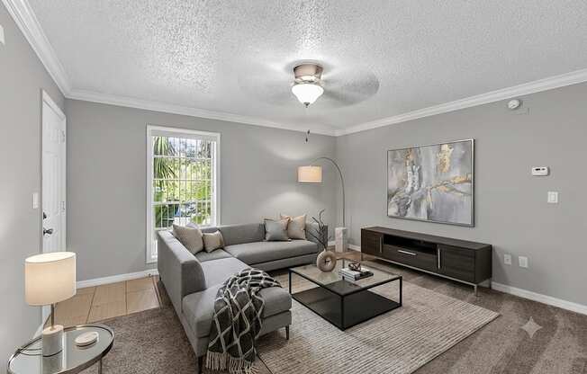 A living room with a grey couch, a coffee table, and a painting on the wall.