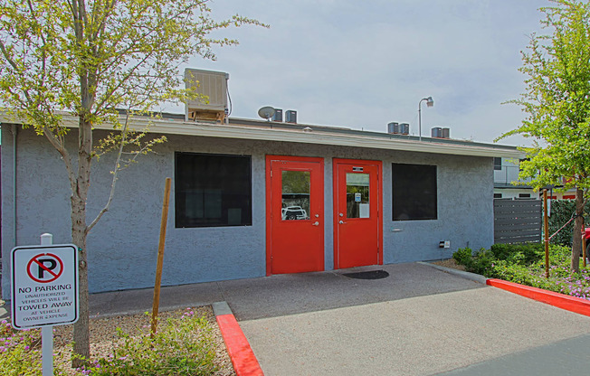 A building with a red door and a no parking sign in front.