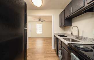A kitchen with a black refrigerator and black stove.