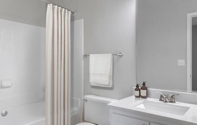 A white bathroom with a white tub, sink, and towel.