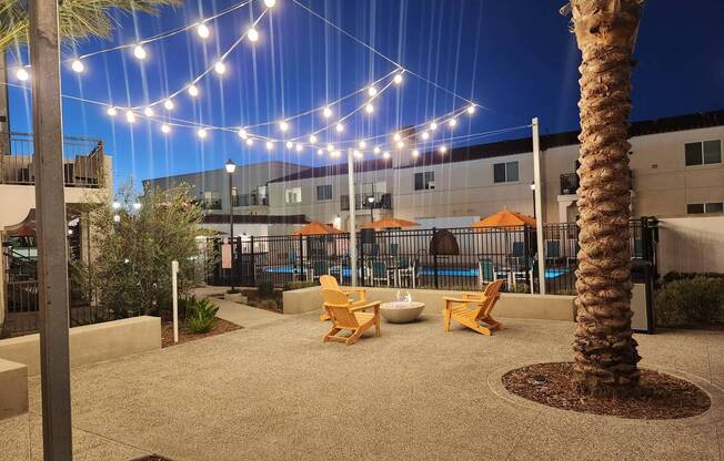 A palm tree is in the foreground of a lit up patio area.