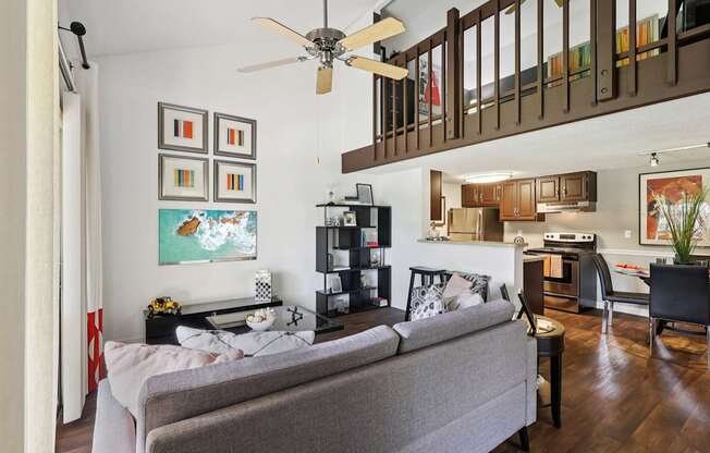 A living room with a grey couch and a ceiling fan.