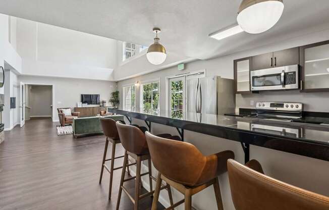 A modern kitchen with brown chairs and a black countertop.