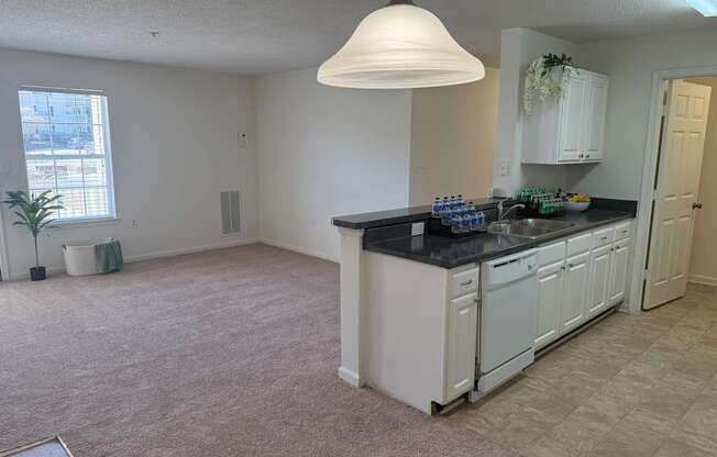 A kitchen with white cabinets and a black countertop.