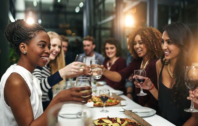 A group of people toasting with wine glasses at a dinner table.
