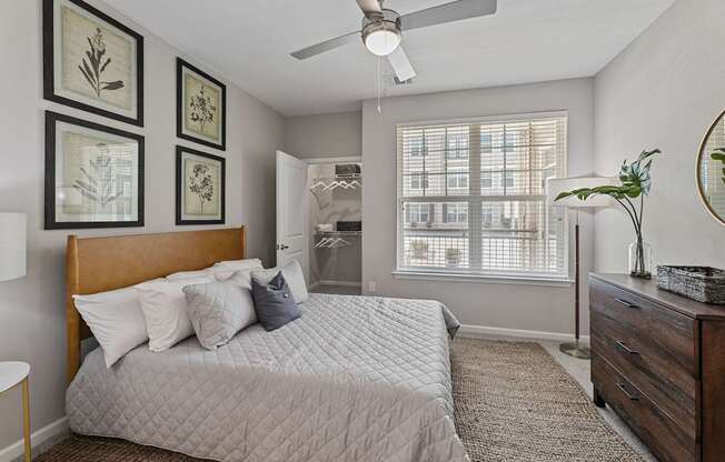 A bedroom with a bed, dresser, and ceiling fan.