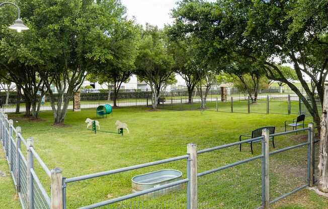 A green fenced area with a playground and trees.