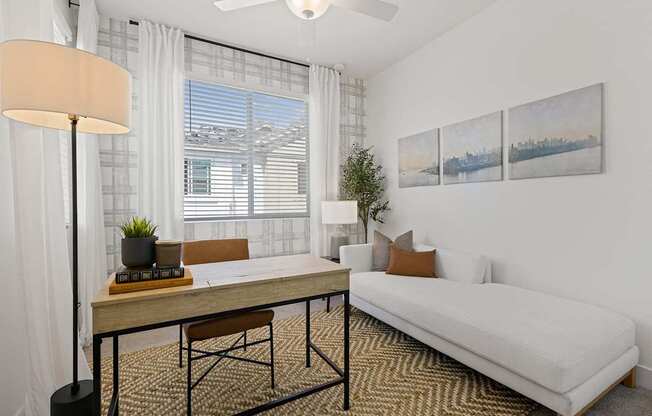 A living room with a white couch, a wooden table, and a ceiling fan.