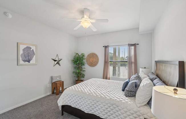 A bedroom with a large bed and a ceiling fan.
