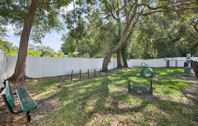 A park with a white fence and a green bench.