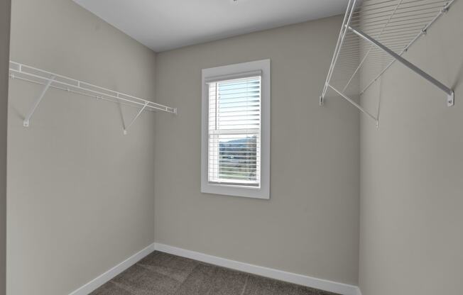 an empty closet with two hanging racks and a window