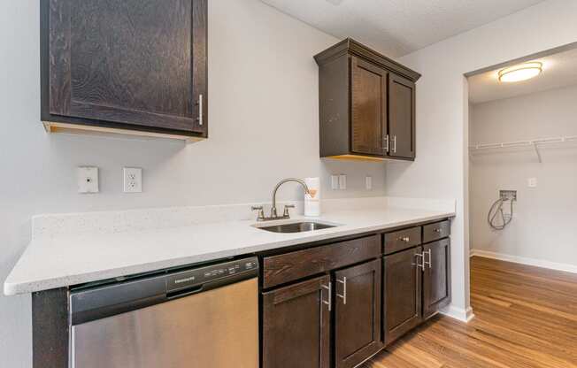 a kitchen with dark cabinets and a sink and a dishwasher