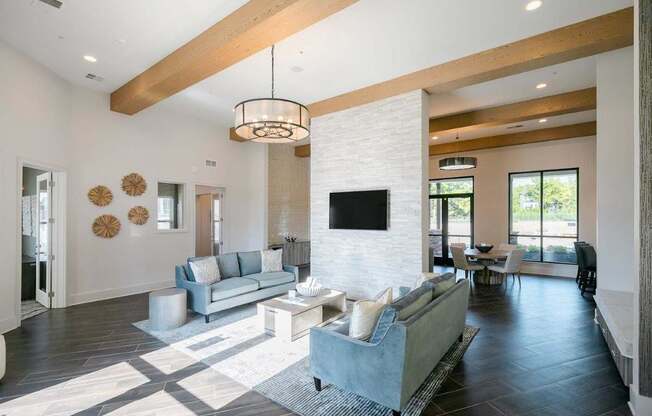 A modern living room with a grey couch and a white brick wall.