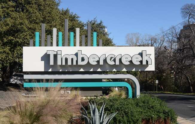 a sign for timbre creek in front of a road and trees