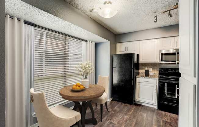 a kitchen with a table and chairs and a black refrigerator