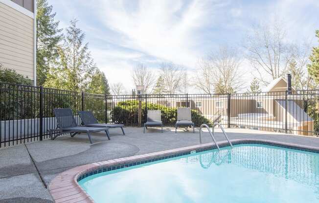 our resort style swimming pool is next to our building with chairs and a fence