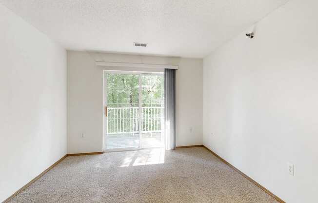 an empty living room with a door to a balcony