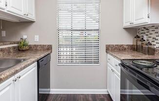 A kitchen with white cabinets and a black stove top oven. at Bradford Pointe, Augusta