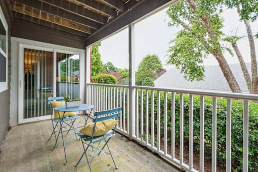 a patio with a table and chairs and a sliding glass door at Woodcreek Apartments, Cary, NC