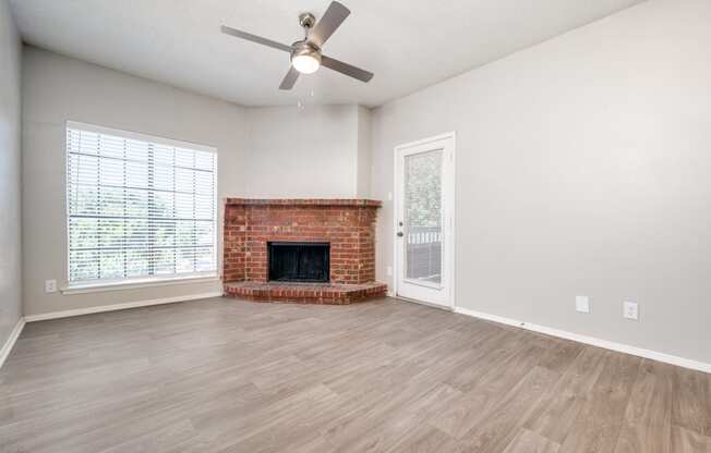 an empty living room with a fireplace and a ceiling fan