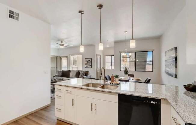 A modern kitchen with a black dishwasher and white cabinets.