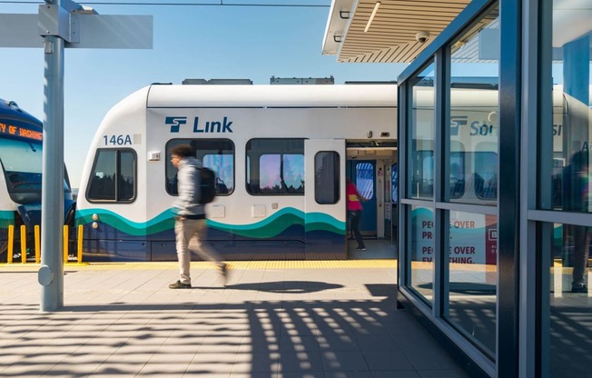 a man walking on a platform in front of a white and blue train at Ion Town Center, Shoreline Washington