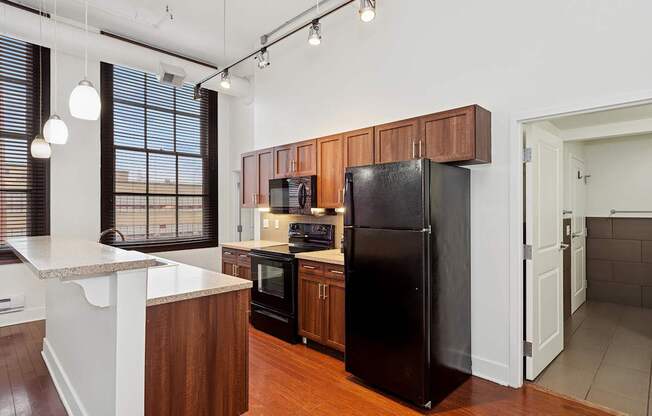 A kitchen with a black refrigerator and wooden cabinets.
