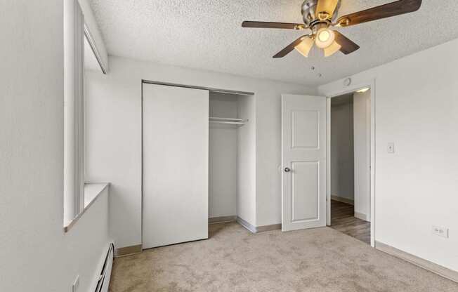 an empty living room with a ceiling fan and a closet