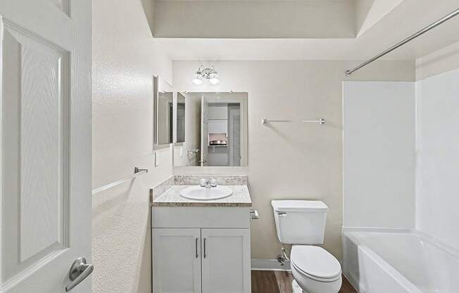 An upgraded bathroom with a toilet, sink, and bathtub at Trappers Cove Apartments, Lansing
