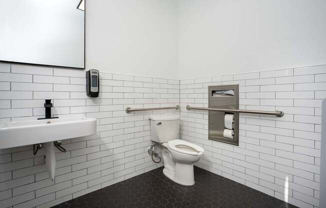 A white toilet in a bathroom with a white sink and a mirror.