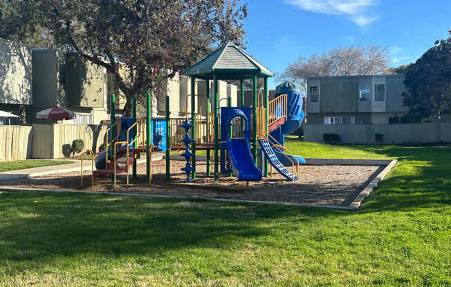 A playground with a blue slide and a green roof.