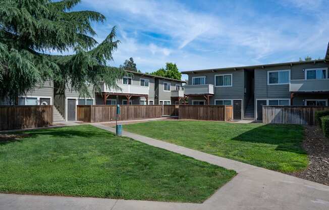 a row of apartment buildings with a lawn and sidewalk