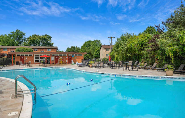A large outdoor swimming pool surrounded by trees and lounge chairs.
