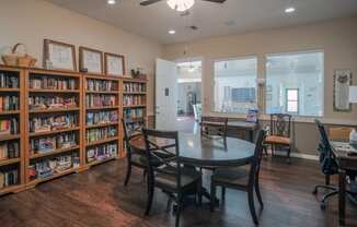 a library with a table and chairs and a book shelf