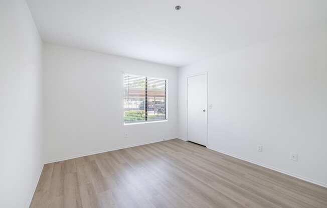 a bedroom with hardwood floors and white walls