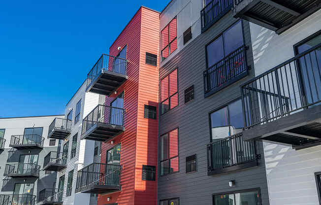 outside of red, gray, and white apartments with balconies
