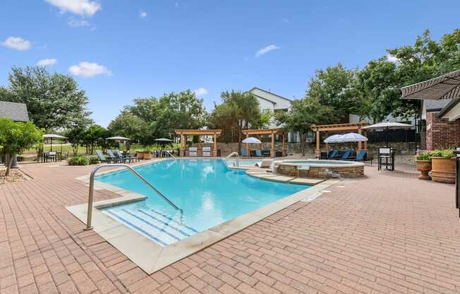 A pool surrounded by a brick patio with a blue sky in the background.