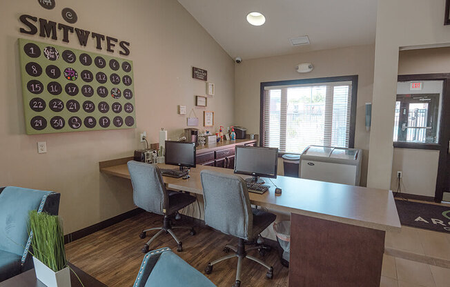 a business center with two desks and three chairs and a window