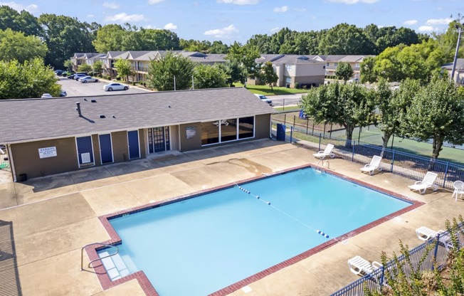 an aerial view of a swimming pool with a building and trees